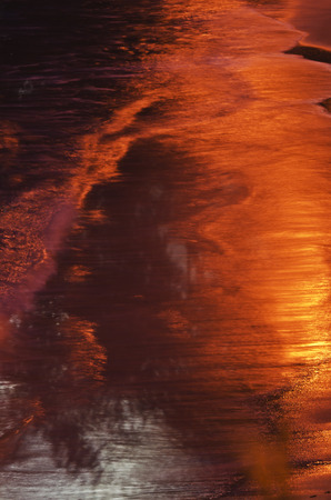 Reflections in the water . Small waves on the beach at night.の写真素材