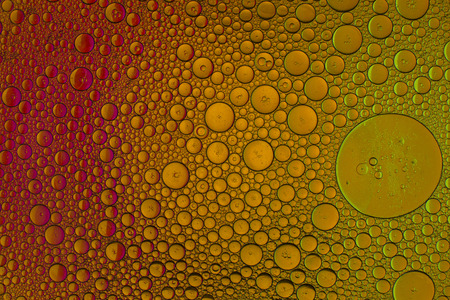 Oil drops in water on a coloured backgroundの写真素材