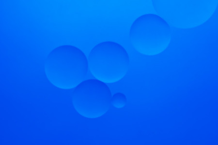 Oil drops in water on a coloured backgroundの写真素材