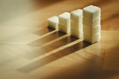 Concept: Ascending stacks of sugar cubes on wooden table with natural light.の写真素材