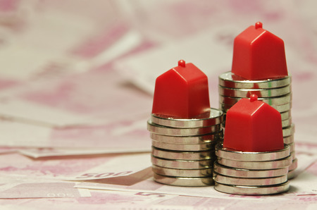 Stack of coins with a red & green houses.の写真素材