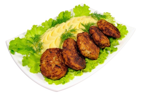 A tasty dish of meat rissole with a garnish of  mashed potatoes and green lettuce and dillの写真素材