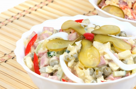 Winter salad Olivier in a white dish on a bamboo napkin backgroundの写真素材