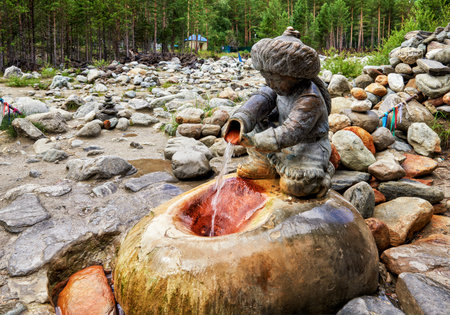 ARSHAN, BURYATIA, RUSSIA - July 17, 2017: Sculpture "Boy with a pitcher" aon mineral spring Hubuun. Healing water flows directly from pitcher of sculpture into stone niche. Popular source for sufferingのeditorial素材