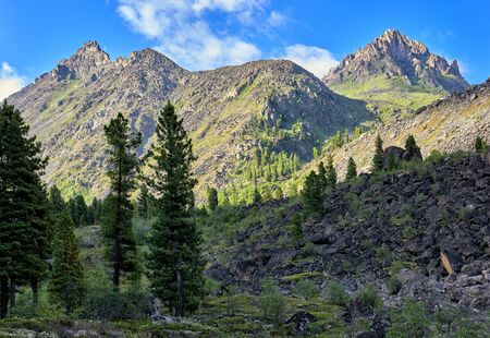 Morning in Siberian mountains. Sunlight illuminates mountains in background, and foreground is still in shadowの写真素材