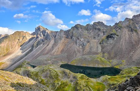 Deep dark lake in a hanging valley under a mountain range. Several lakes are located steps down. Eastern Sayan. Russiaの写真素材
