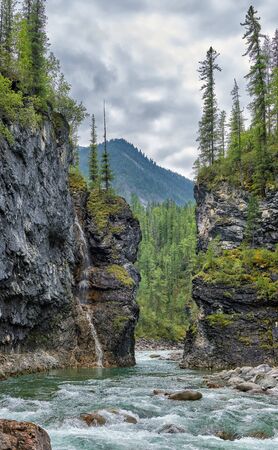 Narrow passage of a mountain river in a clamped canyon. On the cliff is a waterfall from a small stream. River Bilyuty. Eastern Sayan. Buryatiaの写真素材