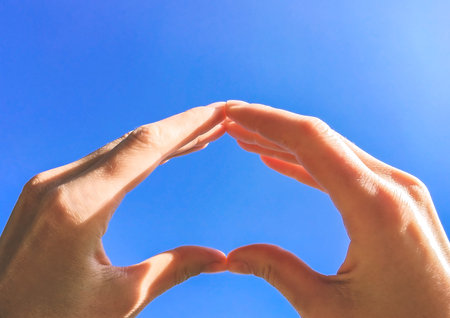 Hands against the sky, hands show heart, a symbol of love