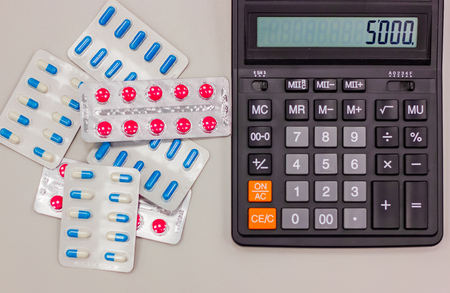 Drugs in the form of tablets lie next to the calculator. close-upの写真素材