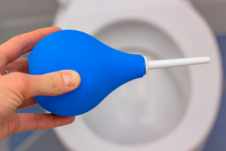 blue medical enema on the background of a white toiletの写真素材