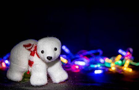 Christmas lights garlands and bear toy on black background. Happy bear in the new year are burning lights festive garlandの写真素材
