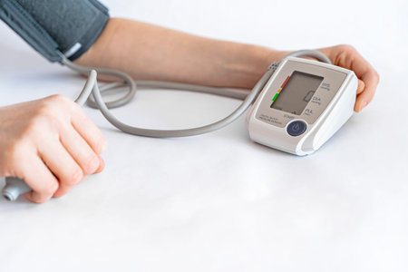 Blood pressure measurement with an electronic device on a white background in close-up.
