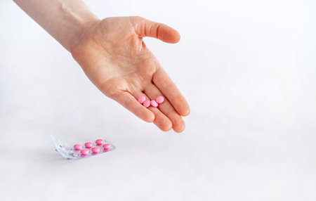 To take the pill, take the pain meds. Tablets in hand on a white background close-up and blurred...