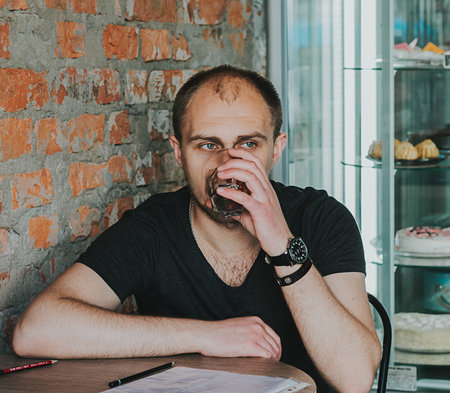 Gorgeous man. Vertical portrait of a handsome young elegant man in a suit having a drinkの写真素材