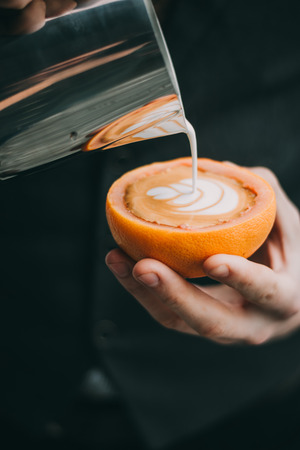 Conceptual Coffee latte art making in a grapefruit cup by baristaの写真素材