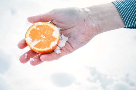A male hand holding an orange slice, over white background with using pathの写真素材