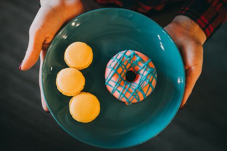Tasty delicious yellow macaroons and donats on blue plateの写真素材