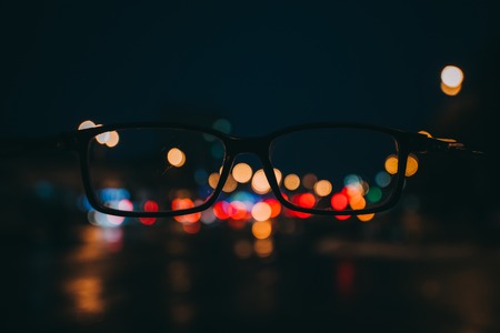 Night cityscape with skyscrapers and city lights as seen through a pair of glasses. Blurred image. bokeh. Night cityの写真素材