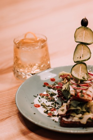 Freshly made club sandwiches with French fries served on white plate.Pressed double toasts with leaf vegetable salad, smoked salmon and cheese served on paper on a wooden table.Street fast food.の写真素材