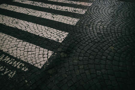 cracked paving stone road with crosswalk and stonesの写真素材
