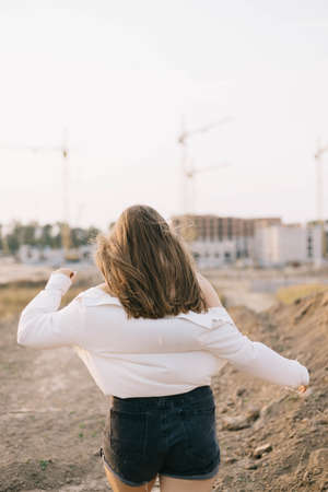 girl in a white shirt walks into sunsetの写真素材