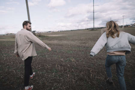 a couple in love walks in an open soybean field in the evening in cloudy weather and hugs a lotの写真素材