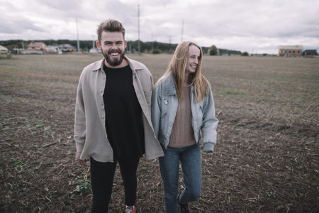 a couple in love walks in an open soybean field in the evening in cloudy weather and hugs a lot