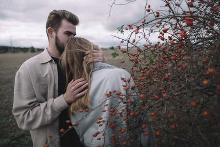 a couple in love walks in an open soybean field in the evening in cloudy weather and hugs a lotの写真素材