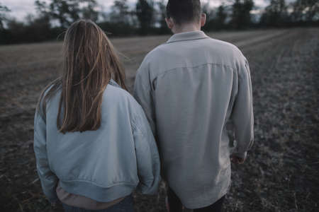 a couple in love walks in an open soybean field in the evening in cloudy weather and hugs a lotの写真素材