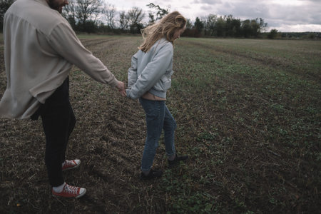 a couple in love walks in an open soybean field in the evening in cloudy weather