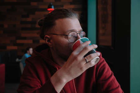 Portrait of happy male freelancer in optical eyewear for vision correction smiling at camera during break from web working online, cheerful hipster blogger sitting in cafe with mockup laptopの写真素材