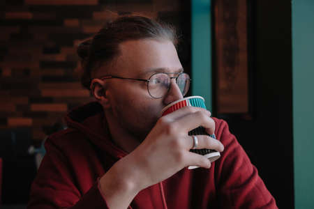 Portrait of happy male freelancer in optical eyewear for vision correction smiling at camera during break from web working online, cheerful hipster blogger sitting in cafe with mockup laptopの写真素材