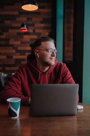Portrait of happy male freelancer in optical eyewear for vision correction smiling at camera during break from web working online, cheerful hipster blogger sitting in cafe with mockup laptopの写真素材