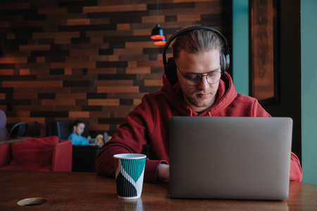 Portrait of happy male freelancer in optical eyewear for vision correction smiling at camera during break from web working online, cheerful hipster blogger sitting in cafe with mockup laptopの写真素材
