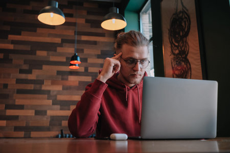 Portrait of happy male freelancer in optical eyewear for vision correction smiling at camera during...