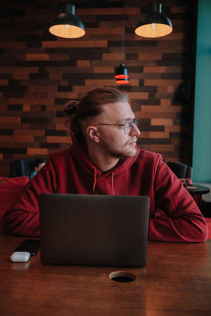 Portrait of happy male freelancer in optical eyewear for vision correction smiling at camera during break from web working online, cheerful hipster blogger sitting in cafe with mockup laptopの写真素材