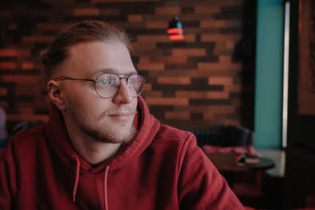 Portrait of happy male freelancer in optical eyewear for vision correction smiling at camera during break from web working online, cheerful hipster blogger sitting in cafe with mockup laptopの写真素材