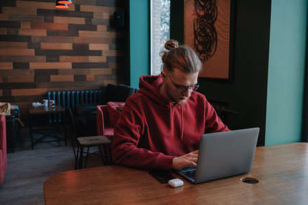 Portrait of happy male freelancer in optical eyewear for vision correction smiling at camera during break from web working online, cheerful hipster blogger sitting in cafe with mockup laptopの写真素材