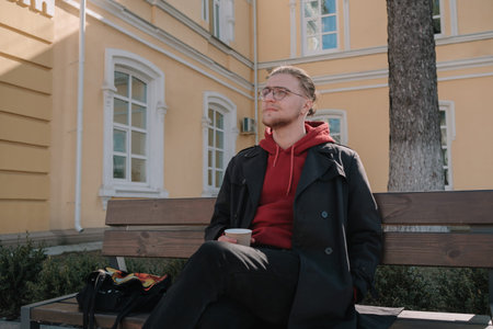 Boy sitting at the bench at the park and writing something