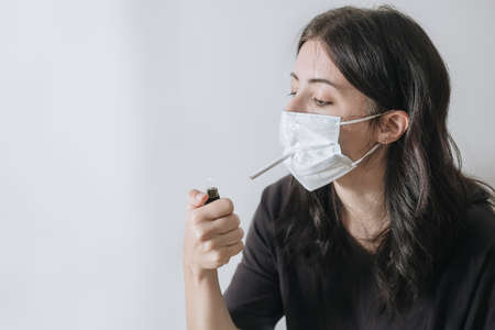 Senior woman hold a cigarette in mouth,withdrawal symptoms,cigarette cravings,feeling stressful while wear a face mask during the pandemicvirus,elderly female is addictedの写真素材