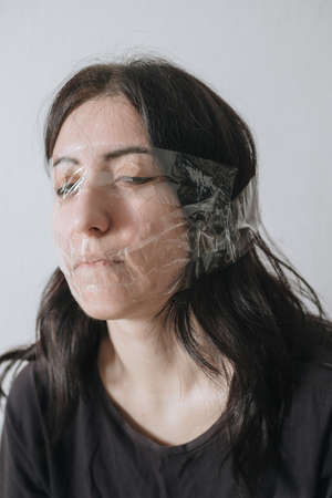 Studio portrait of funny taped woman face on grey background - funny holidayの写真素材