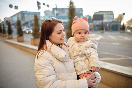 Mother holding baby smiling to camera. Real life authentic casual mom looking to camera holdingの写真素材