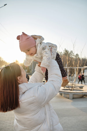 happy harmonious family outdoors. mother throws baby up, laughing and playing in the summer