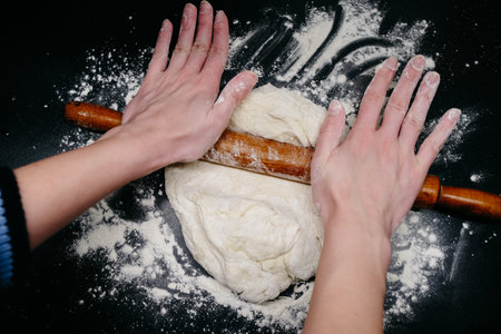Pizza dough on a black table with handsの写真素材