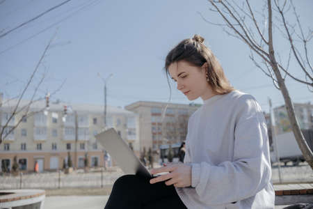Photo of funky adorable young woman sit near fountain break from work look laptop drink coffee wear pants shirt top bag in parkの写真素材