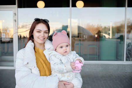 Mother holding baby smiling to camera. Real life authentic casual mom looking to camera holdingの写真素材