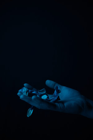 hand on a black background catches falling tulip petals. conceptual