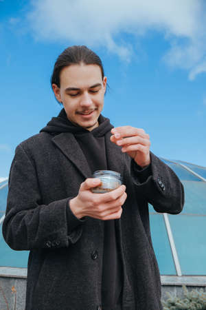 Young gay hipster eating peanuts at the street smiling happy sunglassesの写真素材