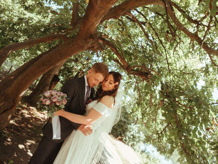 Happy wedding couple walking in a botanical park grain effect authenticの写真素材
