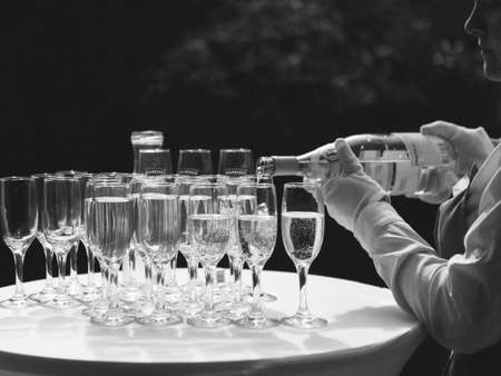 pouring champagne for a toast in a celebratory atmosphere with glasses of champagne on golden flakes bokeh grain effectの写真素材